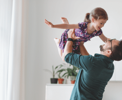 dad holding his daughter above his head, playfully.