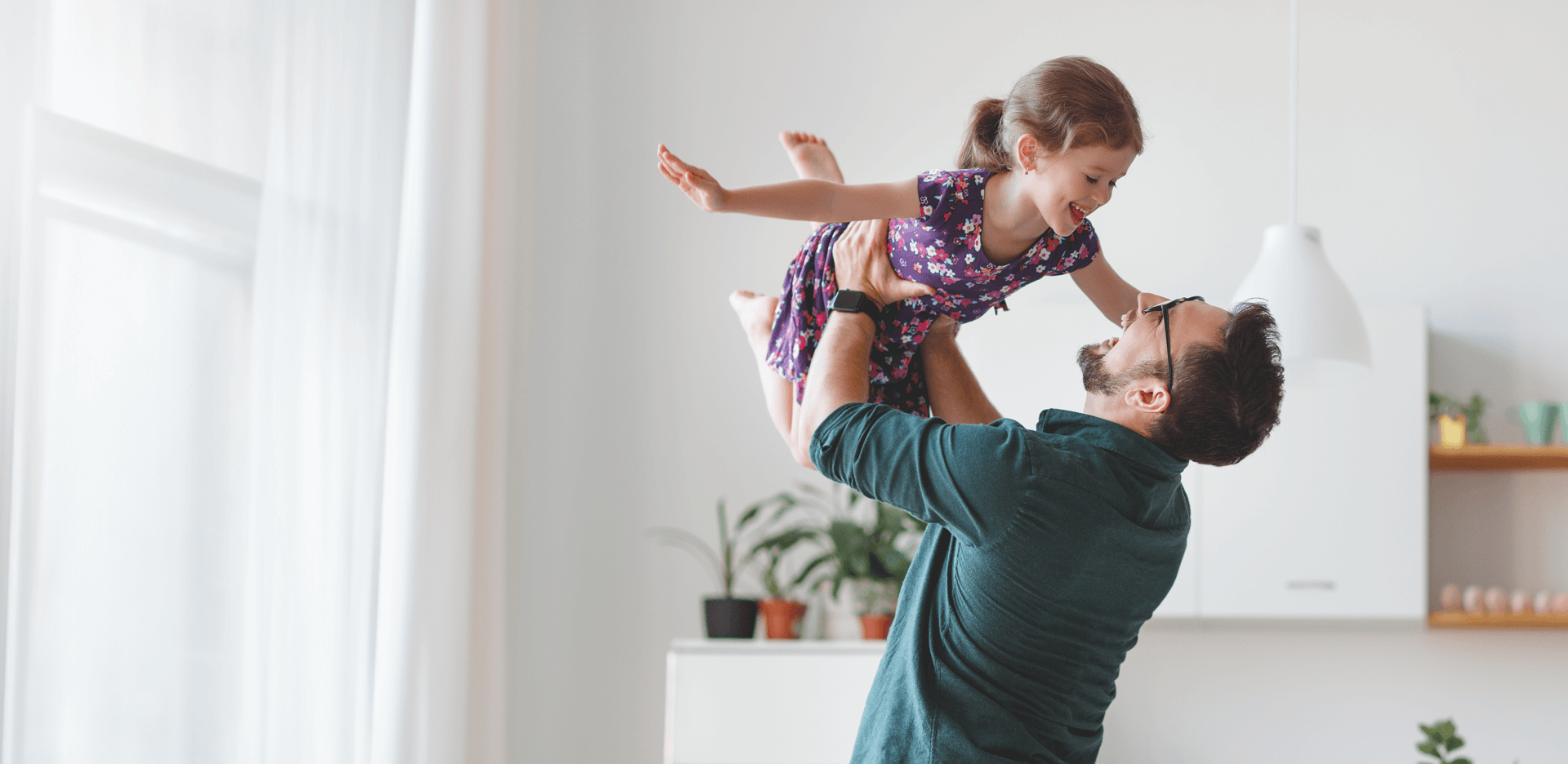 dad holding his daughter above his head, playfully.